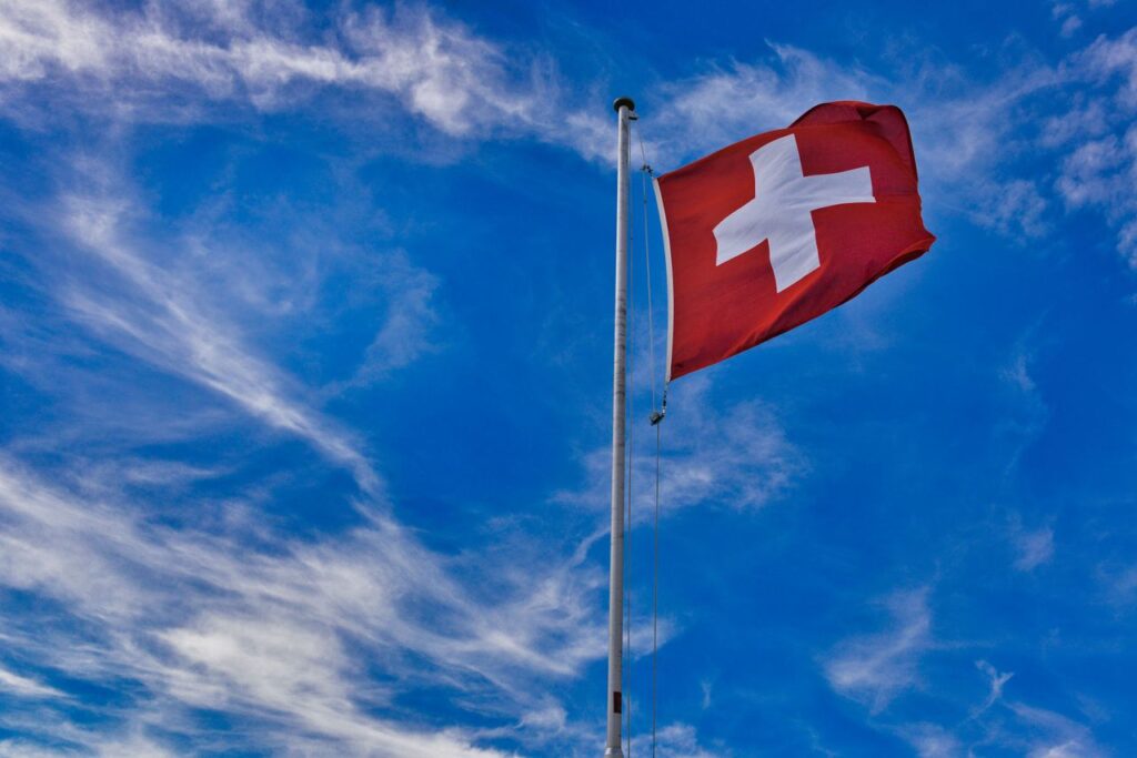 Swiss flag on a mast waving against the vivid blue sky in Grindelwald, Switzerland.