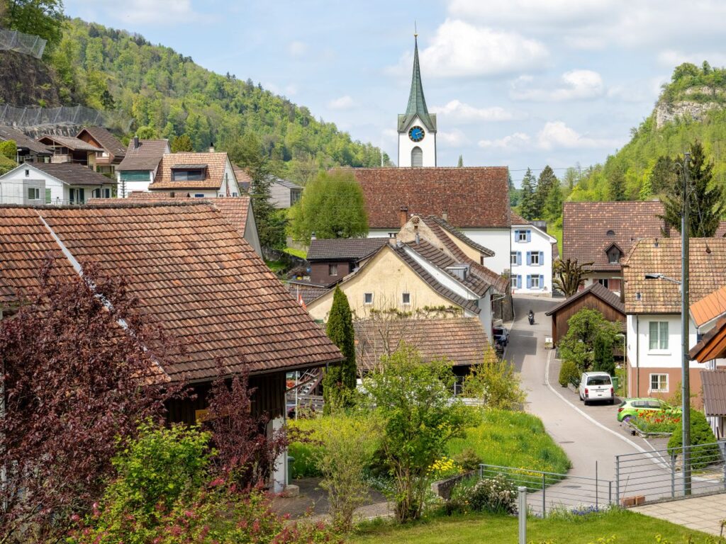 Beautiful village scene with church, houses, and lush greenery in a spring setting.